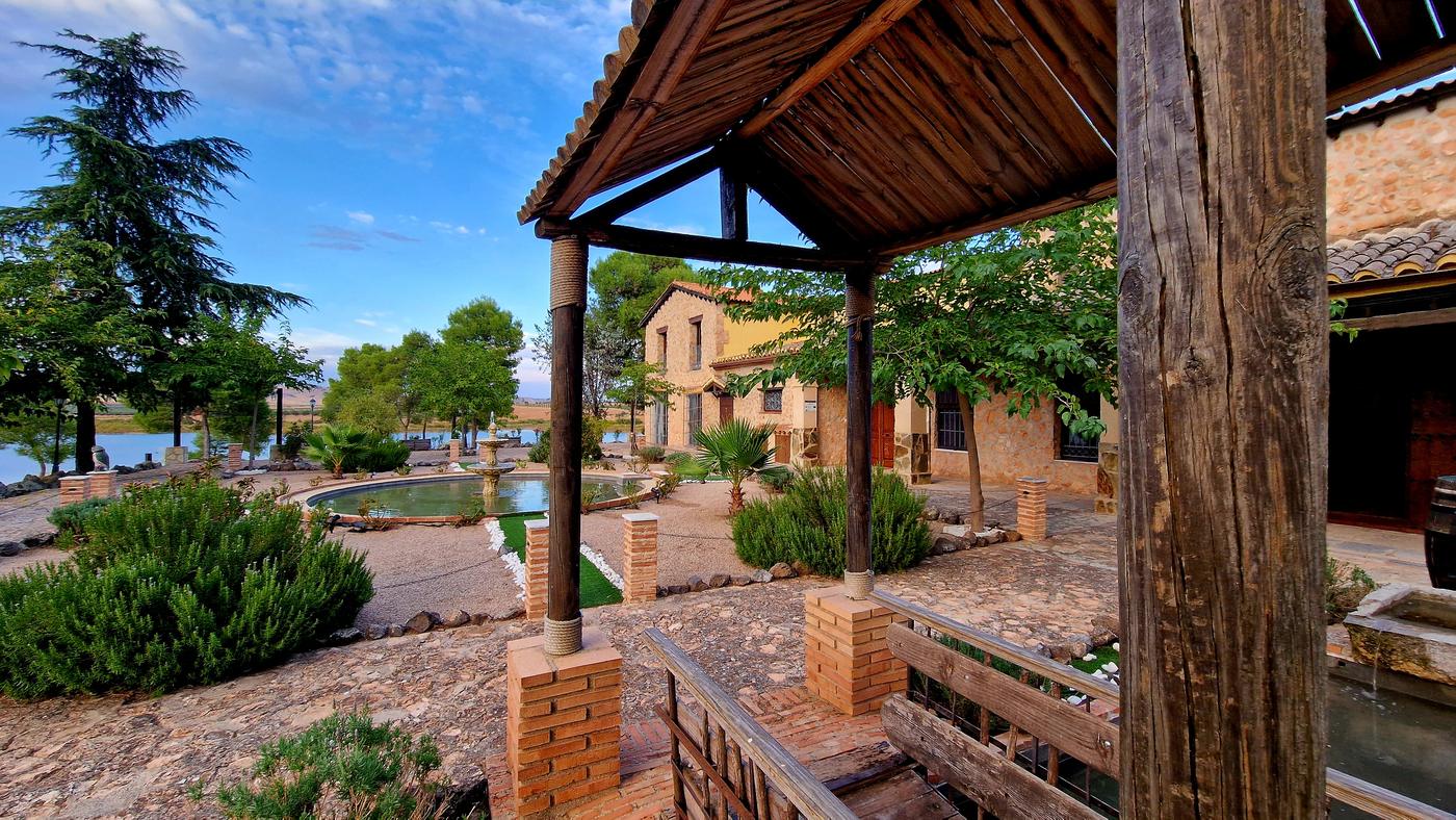 Pérgola de madera junto al estanque y la casa